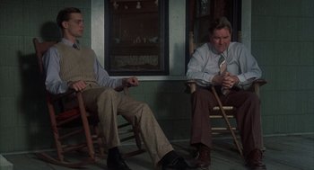 Movie still from “Thieves Like Us” (1974), directed by Robert Altman – Two men sitting in rocking chairs in front of a window; Medium shot, Low angle