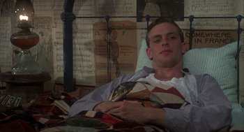 Movie still from “Thieves Like Us” (1974), directed by Robert Altman – A man laying in a bed with a book in front of him; Medium shot, High angle