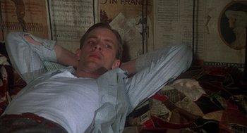 Movie still from “Thieves Like Us” (1974), directed by Robert Altman – A man laying on the floor with his hands behind his head; Medium shot, High angle