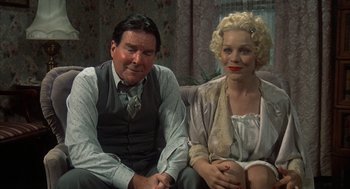 Movie still from “Thieves Like Us” (1974), directed by Robert Altman – A man and a woman sitting next to each other on a couch; Medium shot, High angle