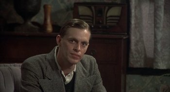 Movie still from “Thieves Like Us” (1974), directed by Robert Altman – A man sitting in front of an old fashioned radio; Close Up shot, Over the shoulder angle