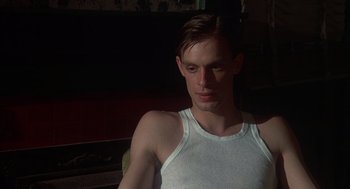 Movie still from “Thieves Like Us” (1974), directed by Robert Altman – A man in a white tank top looking at the camera; Close Up shot, Low angle