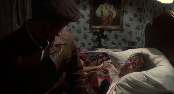 Movie still from “Thieves Like Us” (1974), directed by Robert Altman – Two people in a room with a painting on the wall behind them; Medium shot, High angle