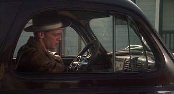 Movie still from “Thieves Like Us” (1974), directed by Robert Altman – A man sitting in the driver's seat of a car; Medium shot, Low angle