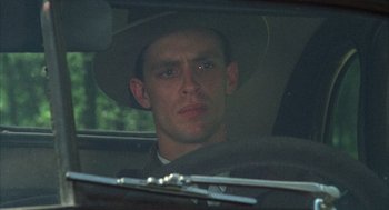 Movie still from “Thieves Like Us” (1974), directed by Robert Altman – A man wearing a hat sitting in the back of a car; Close Up shot, Low angle