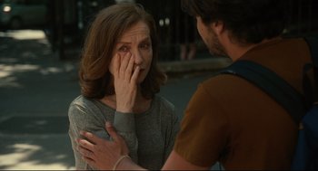 A woman holding her hand up to her face as a man touches her face