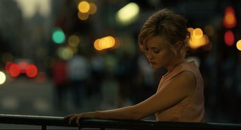 A beautiful young lady sitting on a railing in a city
