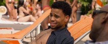 Movie still from “Think Like a Man Too” (2014), directed by Tim Story – A young man sitting on a beach chair with his shirt off; Close Up shot, High angle