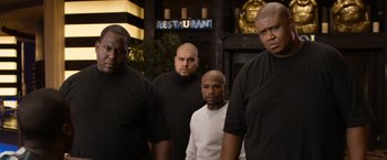 Movie still from “Think Like a Man Too” (2014), directed by Tim Story – A group of men standing next to each other in front of a restaurant; Medium shot, Low angle