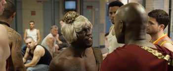 Movie still from “Think Like a Man Too” (2014), directed by Tim Story – A man with a blonde wig and a leopard print hat; Medium shot, Over the shoulder angle