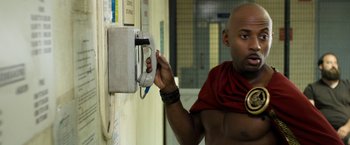 Movie still from “Think Like a Man Too” (2014), directed by Tim Story – A man in a red shirt is holding a phone; Medium shot, Low angle