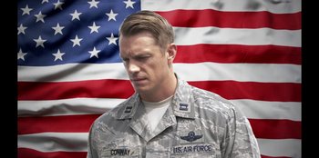 Movie still from “House of Cards” (2013), created by Beau Willimon – A man in a military uniform standing in front of an american flag; Close Up shot, Low angle