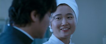Movie still from “Thirst” (2009), directed by Park Chan-wook – A woman in a nurse's uniform smiling at the camera; Close Up shot, Over the shoulder angle