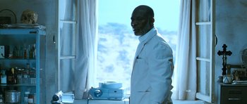 Movie still from “Thirst” (2009), directed by Park Chan-wook – A man standing in front of a window with a projector; Medium shot, Low angle