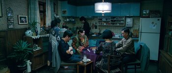 Movie still from “Thirst” (2009), directed by Park Chan-wook – A group of people sitting around a table in a room; Wide shot, High angle