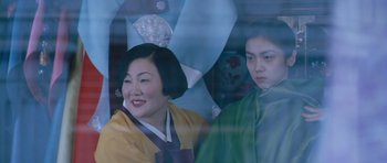 Movie still from “Thirst” (2009), directed by Park Chan-wook – Two women in traditional garb are looking out a window; Medium shot, Over the shoulder angle
