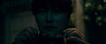 Movie still from “Thirst” (2009), directed by Park Chan-wook – A man holding a pair of glasses in front of his face; Extreme Close Up shot, Low angle