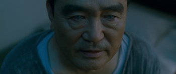 Movie still from “Thirst” (2009), directed by Park Chan-wook – An older man's face is lit up by the light; Close Up shot, High angle
