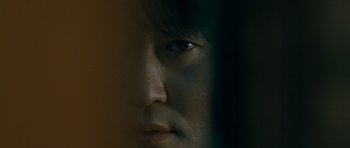 Movie still from “Thirst” (2009), directed by Park Chan-wook – A person's face in a dark room; Extreme Close Up shot, Over the shoulder angle