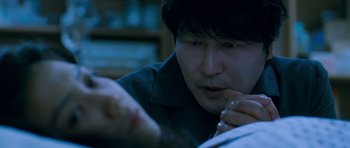 Movie still from “Thirst” (2009), directed by Park Chan-wook – A man looking down at something in his hand; Close Up shot, Over the shoulder angle