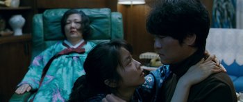 Movie still from “Thirst” (2009), directed by Park Chan-wook – A man and a woman are sitting on a couch; Medium shot, Over the shoulder angle