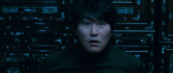 Movie still from “Thirst” (2009), directed by Park Chan-wook – A man in a black shirt is looking at the camera; Close Up shot, Overhead angle