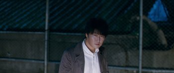Movie still from “Thirst” (2009), directed by Park Chan-wook – A man in a white shirt and a brown jacket; Medium shot, High angle