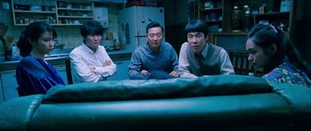 Movie still from “Thirst” (2009), directed by Park Chan-wook – A group of men sitting around a table in a room; Medium shot, High angle