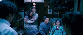 Movie still from “Thirst” (2009), directed by Park Chan-wook – A group of people sitting in a living room together; Medium shot, High angle