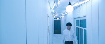Movie still from “Thirst” (2009), directed by Park Chan-wook – A man in a white shirt is walking down a hallway; Wide shot, Low angle