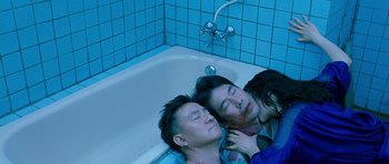 Movie still from “Thirst” (2009), directed by Park Chan-wook – A man and two women laying in a bath tub; Medium shot, Overhead angle