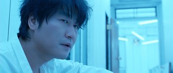 Movie still from “Thirst” (2009), directed by Park Chan-wook – A young man with black hair is looking at the camera; Close Up shot, Low angle