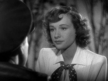 Movie still from “Thirty Seconds Over Tokyo” (1944), directed by Mervyn LeRoy – A black - and - white photo of a woman in a white shirt and a polka dot tie; Close Up shot, Over the shoulder angle
