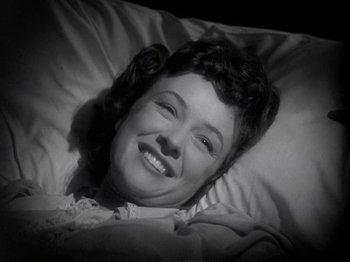 Movie still from “Thirty Seconds Over Tokyo” (1944), directed by Mervyn LeRoy – A woman laying in a bed smiling for the camera; Close Up shot, High angle