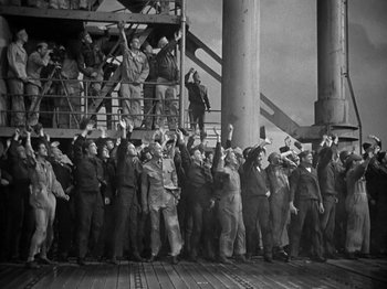 Movie still from “Thirty Seconds Over Tokyo” (1944), directed by Mervyn LeRoy – A group of men standing on top of a wooden platform; Wide shot, High angle