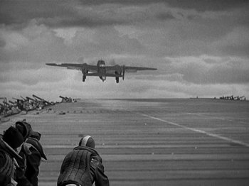 Movie still from “Thirty Seconds Over Tokyo” (1944), directed by Mervyn LeRoy – An airplane is taking off from an airport runway; Wide shot, Low angle
