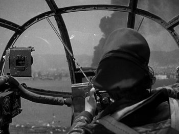 Movie still from “Thirty Seconds Over Tokyo” (1944), directed by Mervyn LeRoy – A man in the cockpit of an airplane taking a picture; Medium shot, Low angle