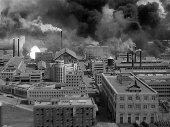 Movie still from “Thirty Seconds Over Tokyo” (1944), directed by Mervyn LeRoy – An aerial view of an industrial area with smoke billowing out of the stacks; Extreme Wide shot, High angle