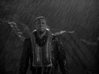 Movie still from “Thirty Seconds Over Tokyo” (1944), directed by Mervyn LeRoy – A man in a life jacket standing in the rain; Medium shot, High angle