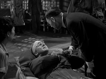 Movie still from “Thirty Seconds Over Tokyo” (1944), directed by Mervyn LeRoy – An old photo of a man talking to another man in a hospital bed; Medium shot, High angle