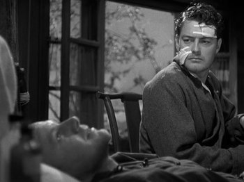 Movie still from “Thirty Seconds Over Tokyo” (1944), directed by Mervyn LeRoy – A man sitting next to another man who is lying on a bed; Close Up shot, Over the shoulder angle