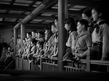 Movie still from “Thirty Seconds Over Tokyo” (1944), directed by Mervyn LeRoy – A group of people sitting in a row on top of a bench; Wide shot, Low angle