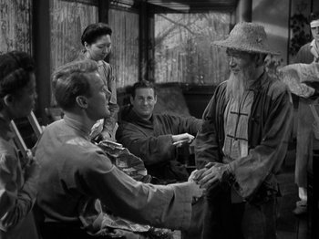 Movie still from “Thirty Seconds Over Tokyo” (1944), directed by Mervyn LeRoy – A group of men shaking hands in front of a building; Medium shot, Over the shoulder angle