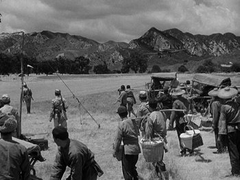 Movie still from “Thirty Seconds Over Tokyo” (1944), directed by Mervyn LeRoy – A black and white photo of a group of people in a field; Extreme Wide shot, High angle