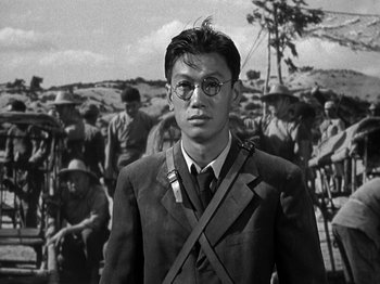 Movie still from “Thirty Seconds Over Tokyo” (1944), directed by Mervyn LeRoy – A man in a suit and tie standing in front of a group of soldiers; Close Up shot, Low angle
