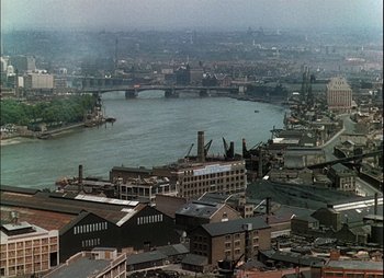 Movie still from “This Happy Breed” (1944), directed by David Lean – An aerial view of a city with a river and a bridge; Extreme Wide shot, High angle