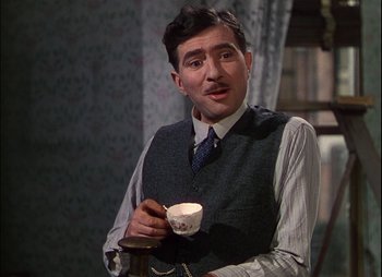 Movie still from “This Happy Breed” (1944), directed by David Lean – A man holding a coffee cup while standing next to a coffee grinder; Close Up shot, Over the shoulder angle