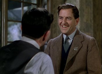 Movie still from “This Happy Breed” (1944), directed by David Lean – A man wearing a suit and tie talking to another man wearing a suit and tie; Medium shot, Over the shoulder angle