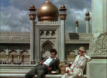 Movie still from “This Happy Breed” (1944), directed by David Lean – A man and a woman sitting on a bench in front of a building; Wide shot, Low angle