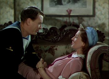Movie still from “This Happy Breed” (1944), directed by David Lean – A man and a woman sitting on a couch talking to each other; Medium shot, High angle